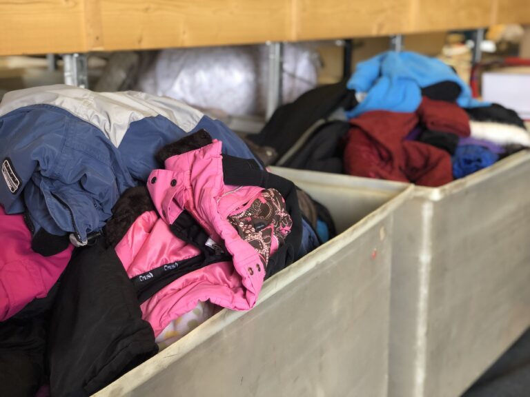 Two large laundry bins full of winter coats